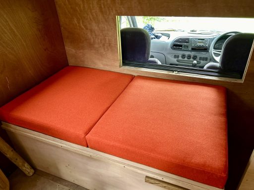 A cosy seating area with orange cushions and a view of a car interior.